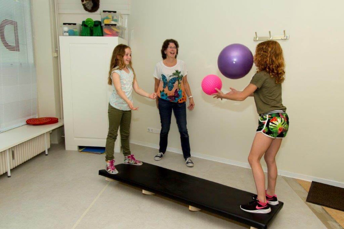 Kinderen oefenen balans op een balansplank met ballen bij Dudok Kinderfysiotherapie