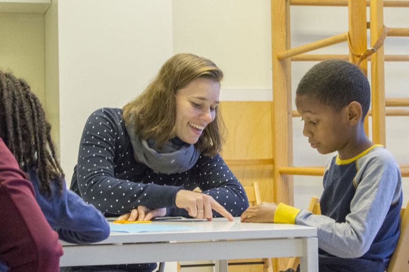 Kinderfysiotherapeut in gesprek met een kind aan tafel tijdens de intake