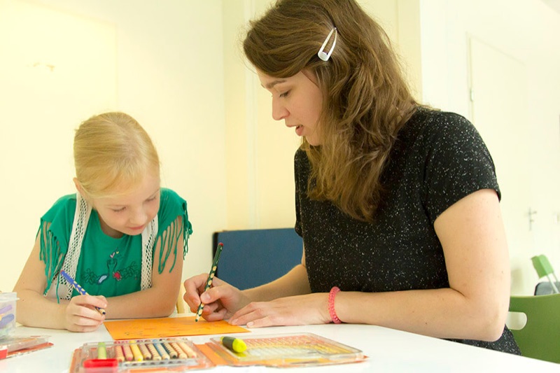 Kinderfysiotherapeut observeert een kind tijdens het schrijven